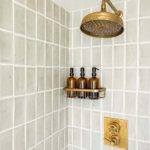 Shower with neutral grey tiles and brass shower head