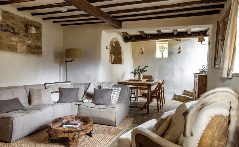 Cosy cottage living and dining room with exposed beams and rustic modern furnishings