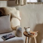 Coffee on a wooden stool by a cosy armchair