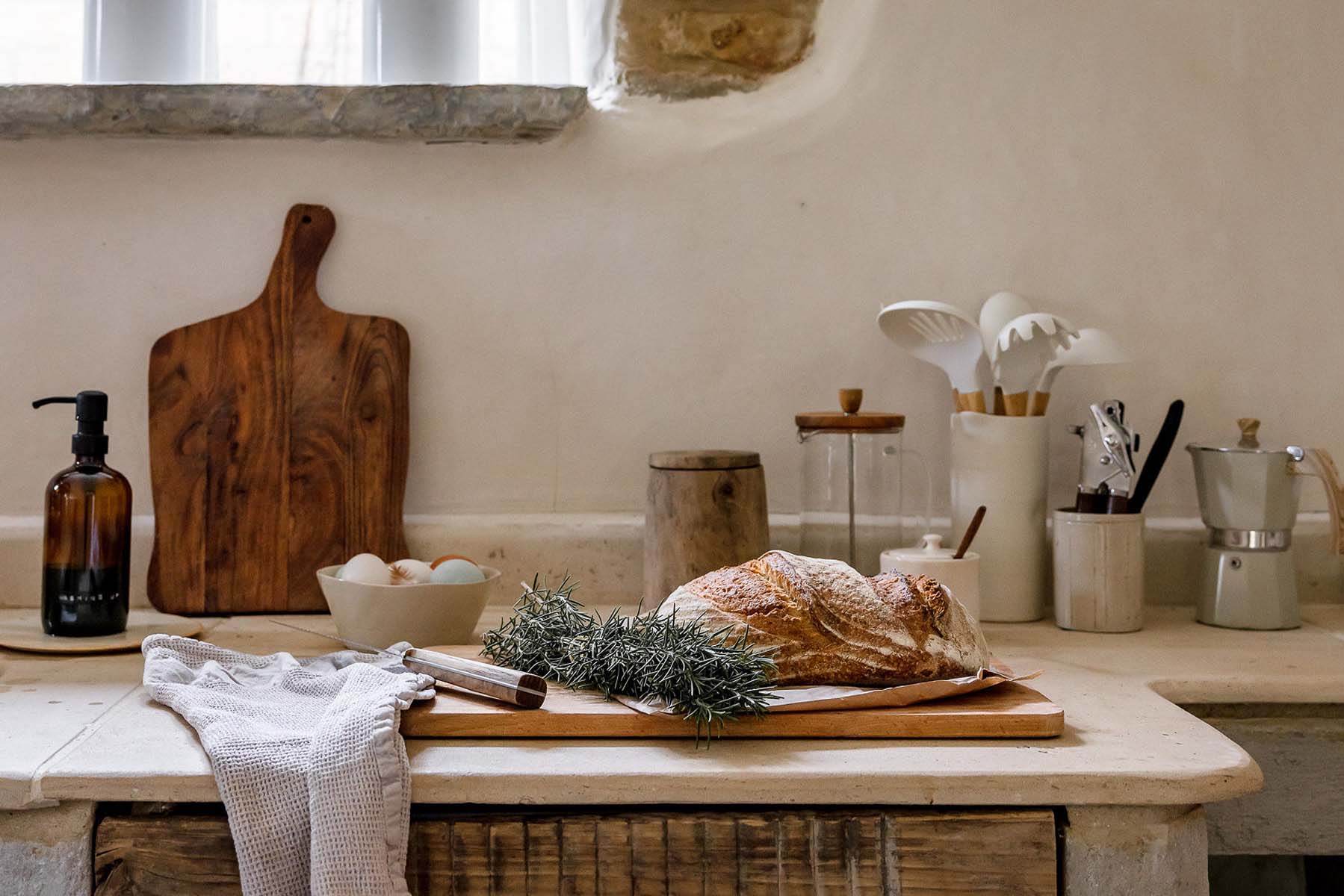 Rustic loaf of bread and a bunch of herbs on a cottage kitchen counter