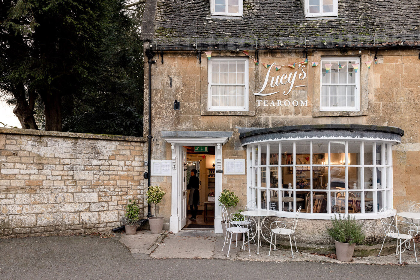 A honey coloured stone village cafe with white windows