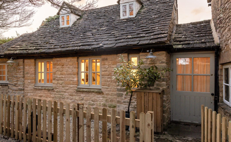 Honey coloured stone cottage with a wooden fence