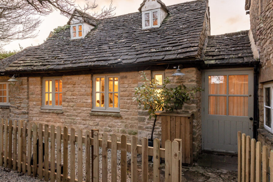 Honey coloured stone cottage with a wooden fence