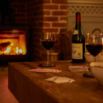 card game and red wine glasses by fireplace