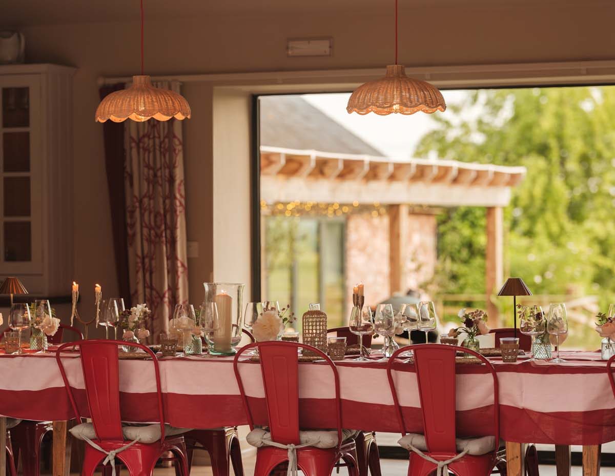 long red table laid up for feasting with rattan shades overhead and double doors opening up onto countryside