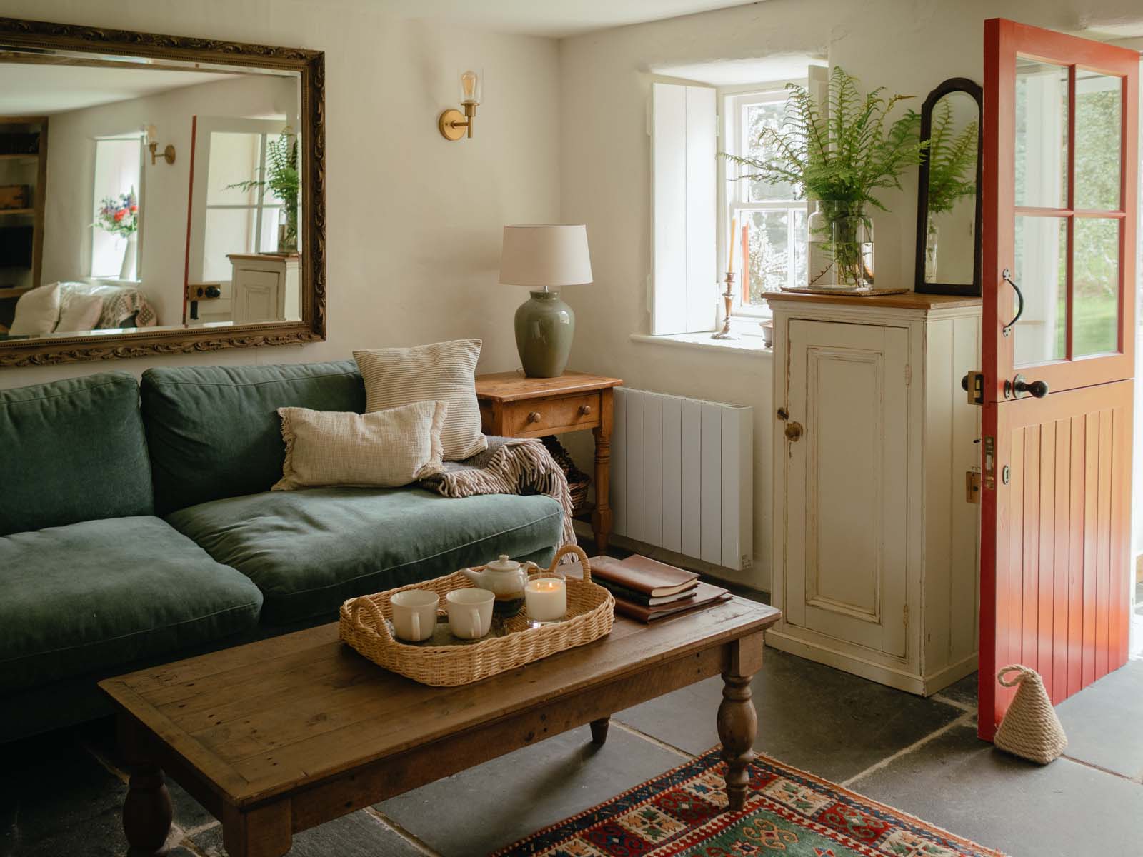 corner of a cosy living room with blue sofa and rattan tray with tea for two on a coffee table