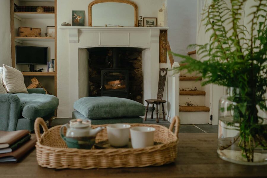 cosy living room set up with a lit log burner and tea for two on rattan tray