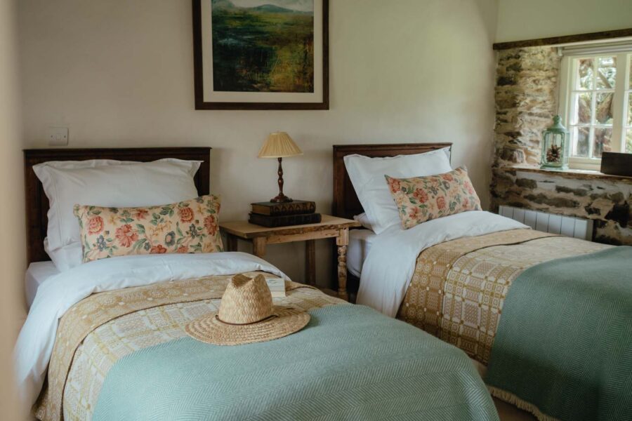 twin beds made up with matching floral cushions and blue bedspreads
