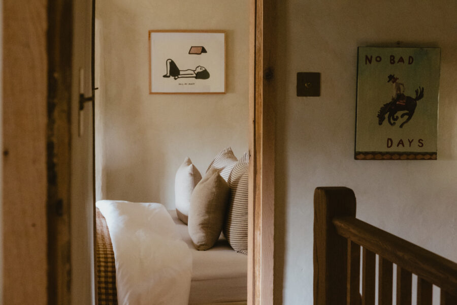 Landing view past a wooden staircase rail toward a daybed, with framed prints including a 