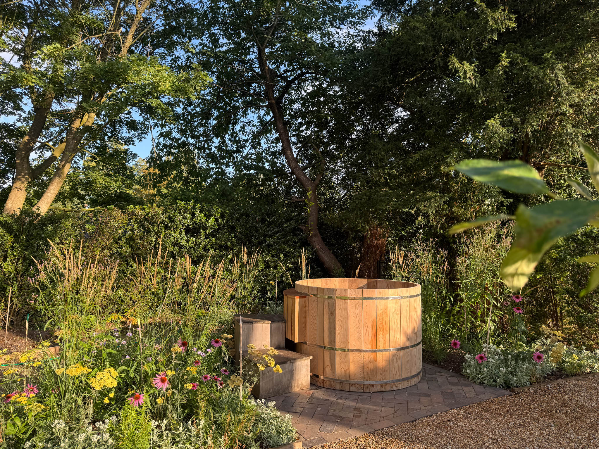 hot tub in garden surrounded by trees and flowers